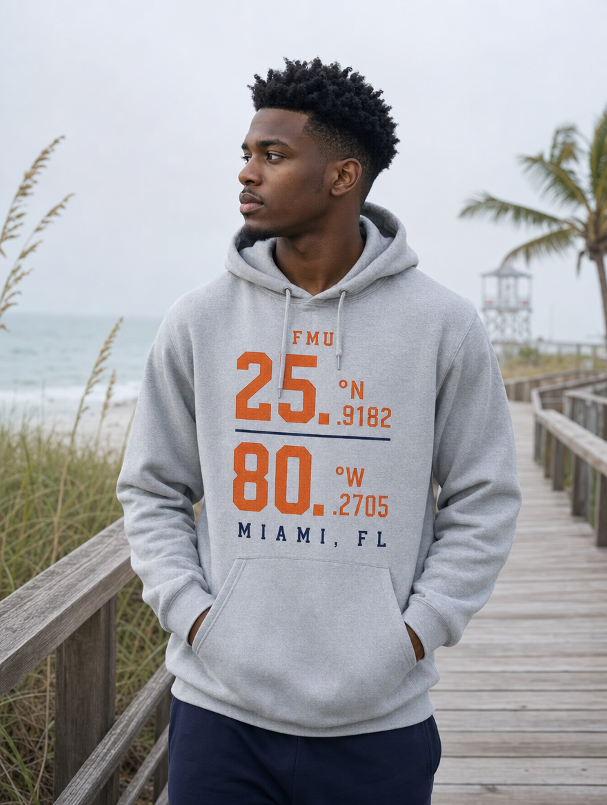 Model wearing grey FMU Coordinates hoodie, orange & navy print, on a Miami boardwalk at the beach
