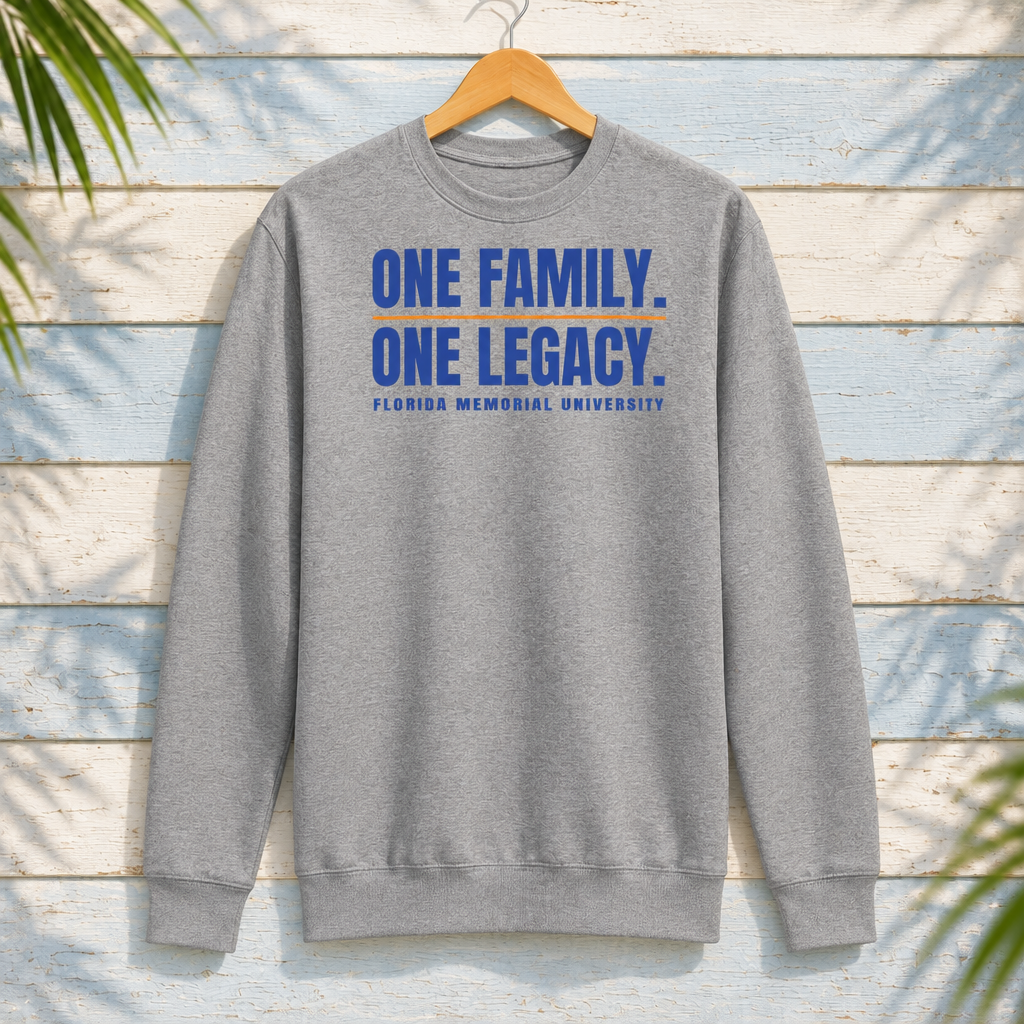 Florida Memorial University One Family. One Legacy. Carbon Grey crewneck with blue lettering and orange divider, front-facing on a hanger against pale-blue clapboard; creative mockup.