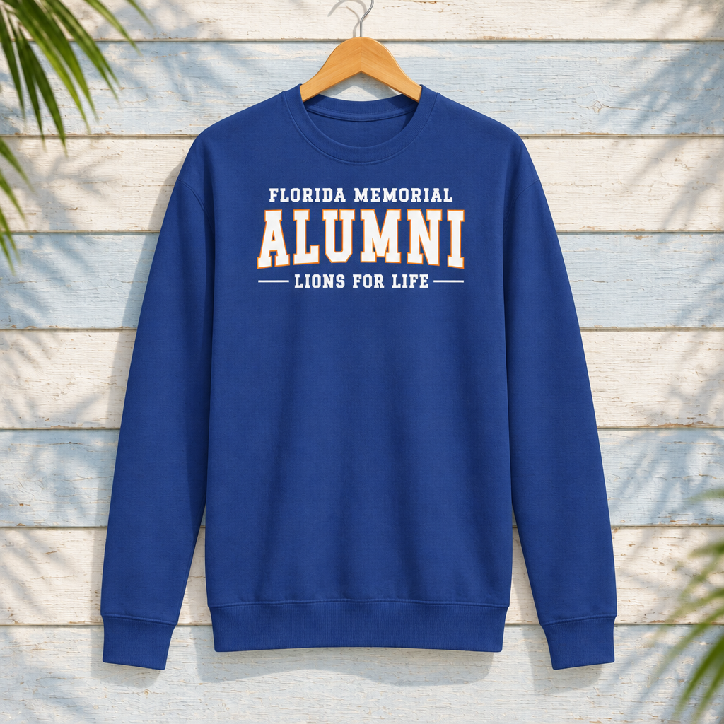 Florida Memorial University Lions for Life Team Royal crewneck with white alumni lettering and orange ALUMNI outline, front-facing on a hanger against pale-blue clapboard; creative mockup.