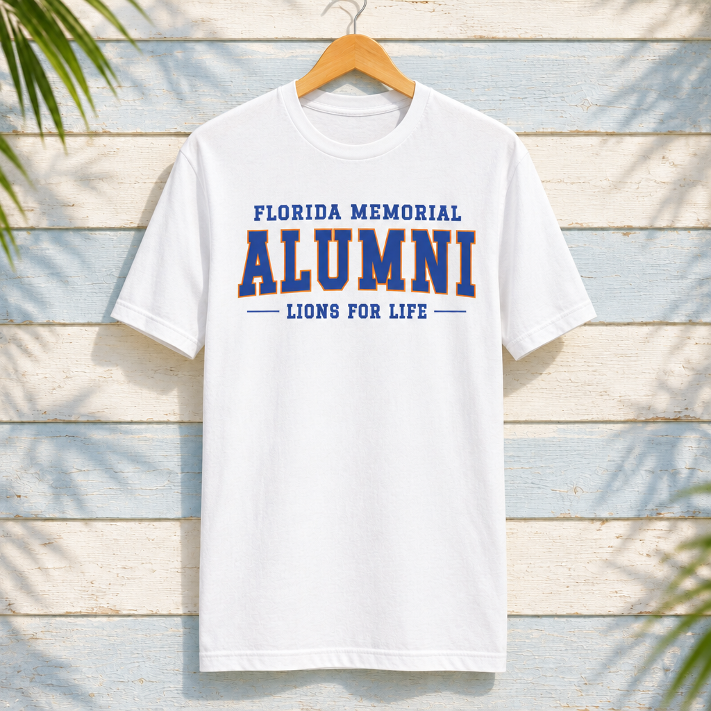 Florida Memorial University Lions for Life white T-shirt with blue alumni lettering and orange ALUMNI outline, front-facing on a hanger against pale-blue clapboard; creative mockup.