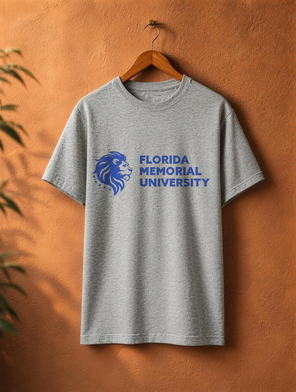 Florida Memorial University Stacked Wordmark tee in athletic heather on a wooden hanger against a textured terracotta wall