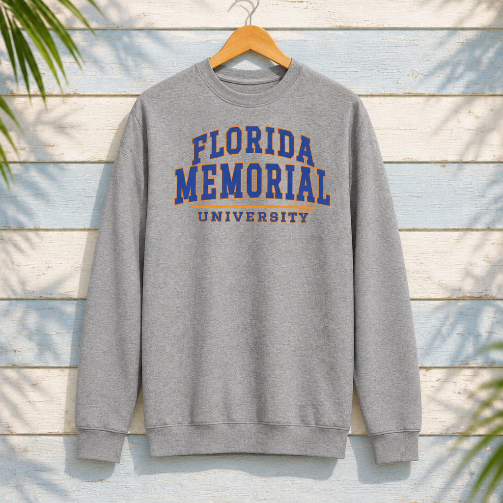 Florida Memorial University Varsity Essentials Carbon Grey crewneck with blue-and-orange collegiate lettering and orange divider, front-facing on a hanger against pale-blue clapboard; creative mockup.