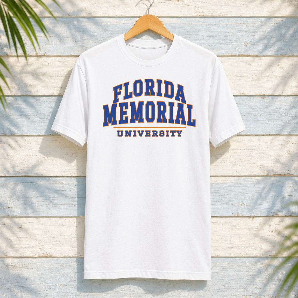 Florida Memorial University Varsity Essentials white T-shirt with blue-and-orange collegiate lettering and orange divider, displayed front-facing on a hanger against pale-blue clapboard; creative mockup.